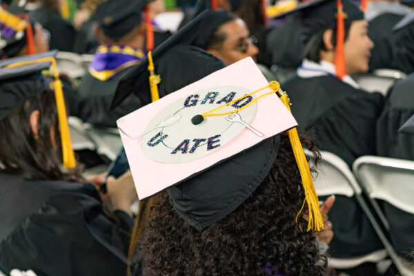 A person wearing a graduation cap that says "graduate."