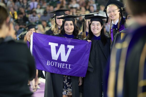 students at 2024 commencement holding up a uw bothell flag