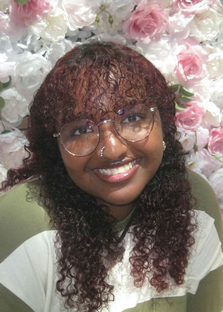 Image of Cecilia Negash sitting in front of a background of flowers