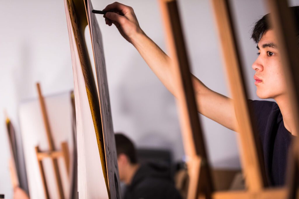 Students drawing with charcoal on an easel