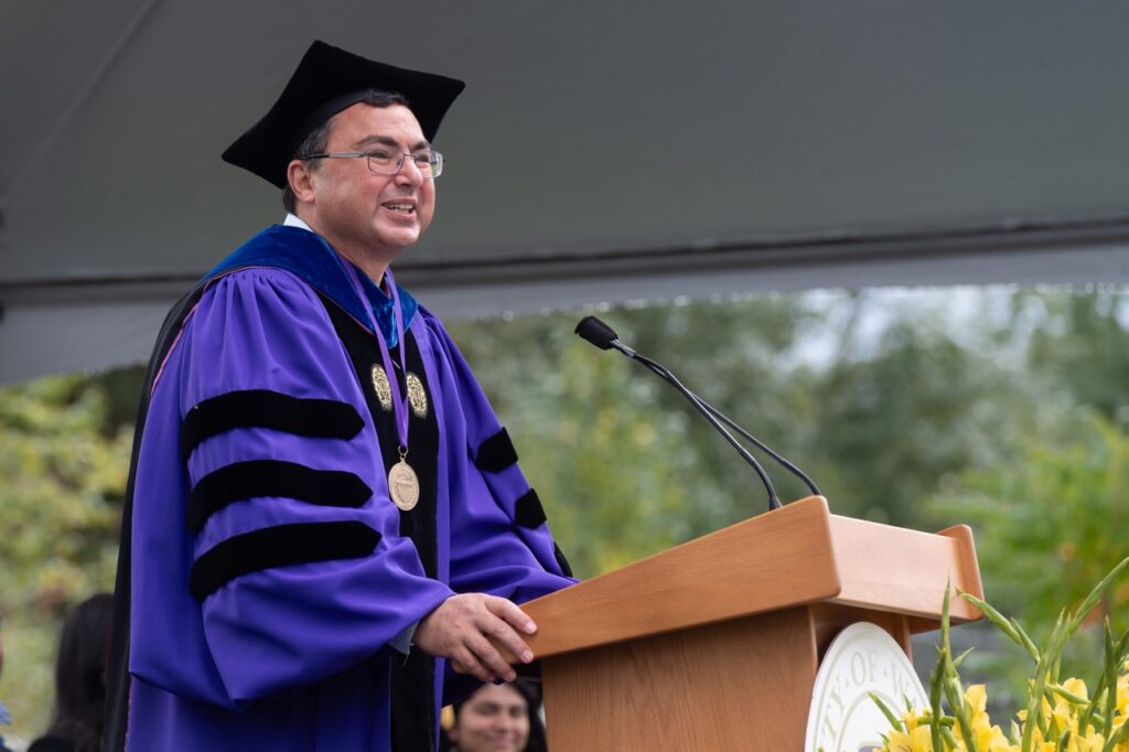 A person in academic regalia at a podium.