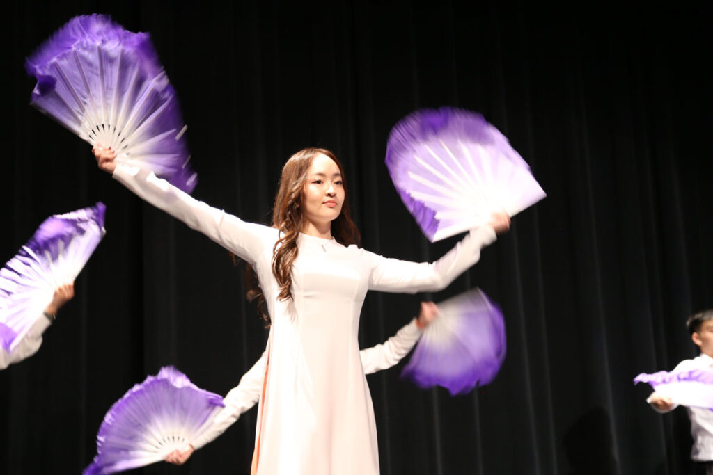 A person holding up two fans.