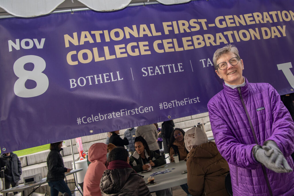 A person in front of a sign that reads "National First-Generation College Celebration."