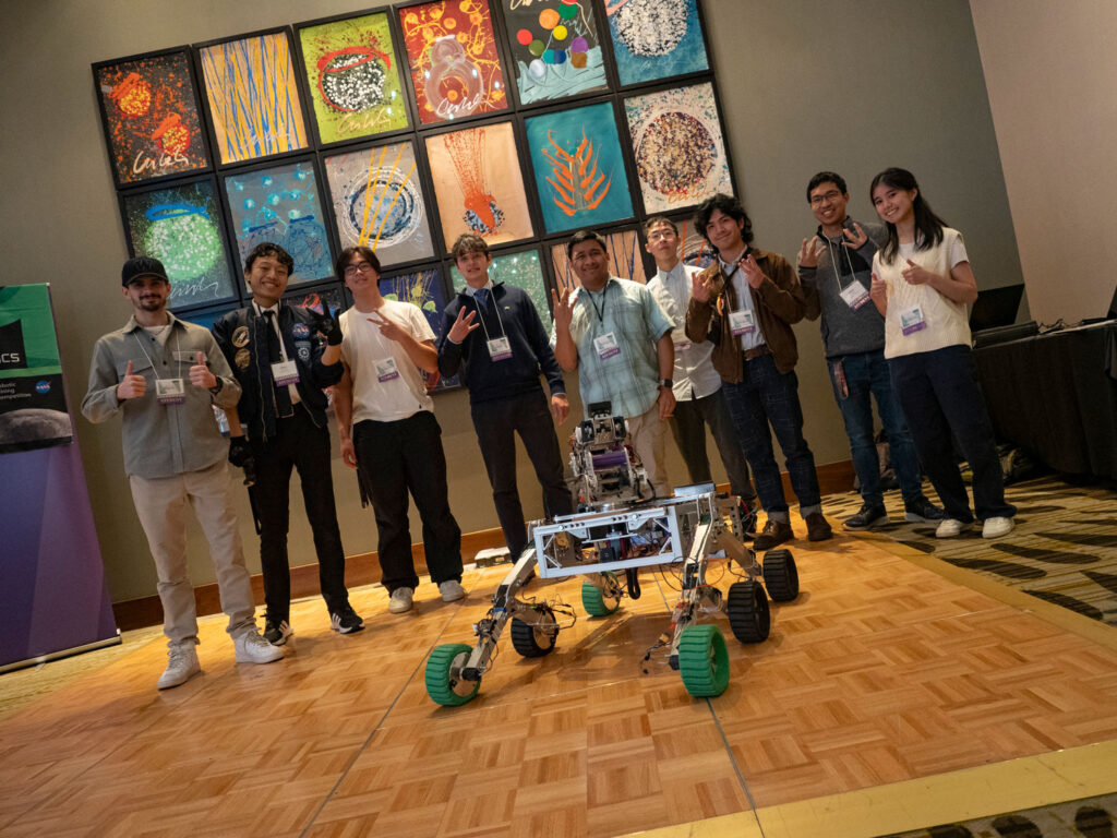 A group of people pose for a photo with a robot.