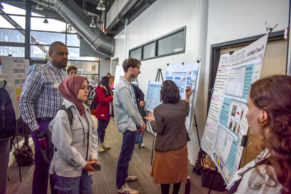 A crowd of people looking at posters.