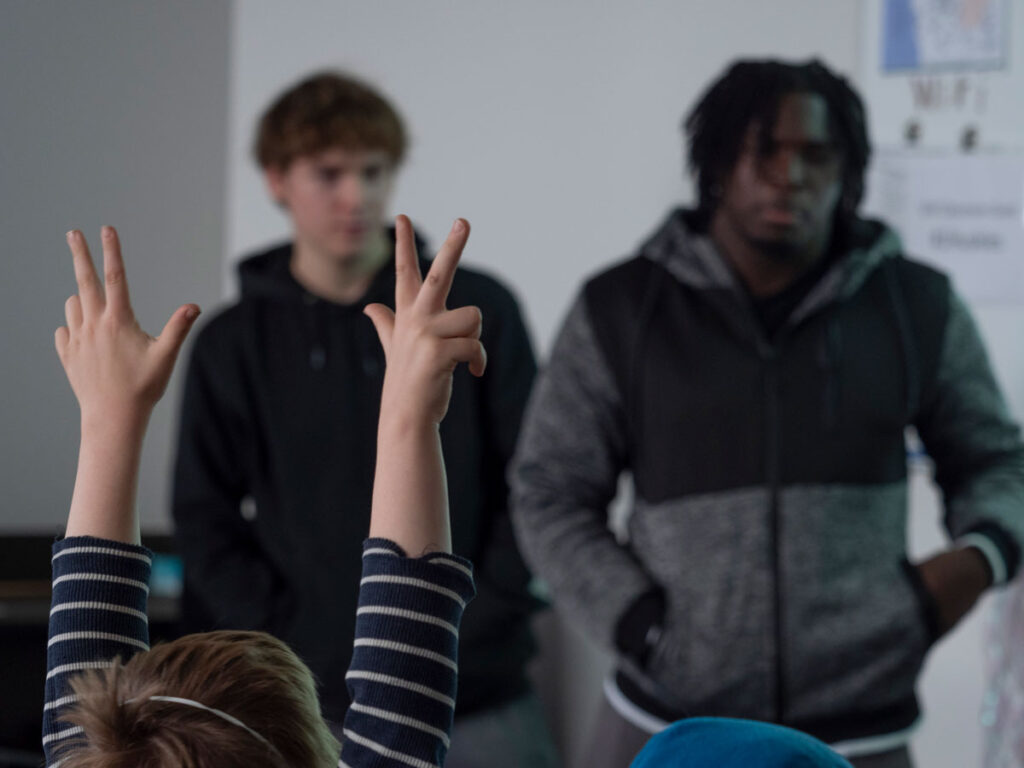 A person raising their hands with two people in the background.