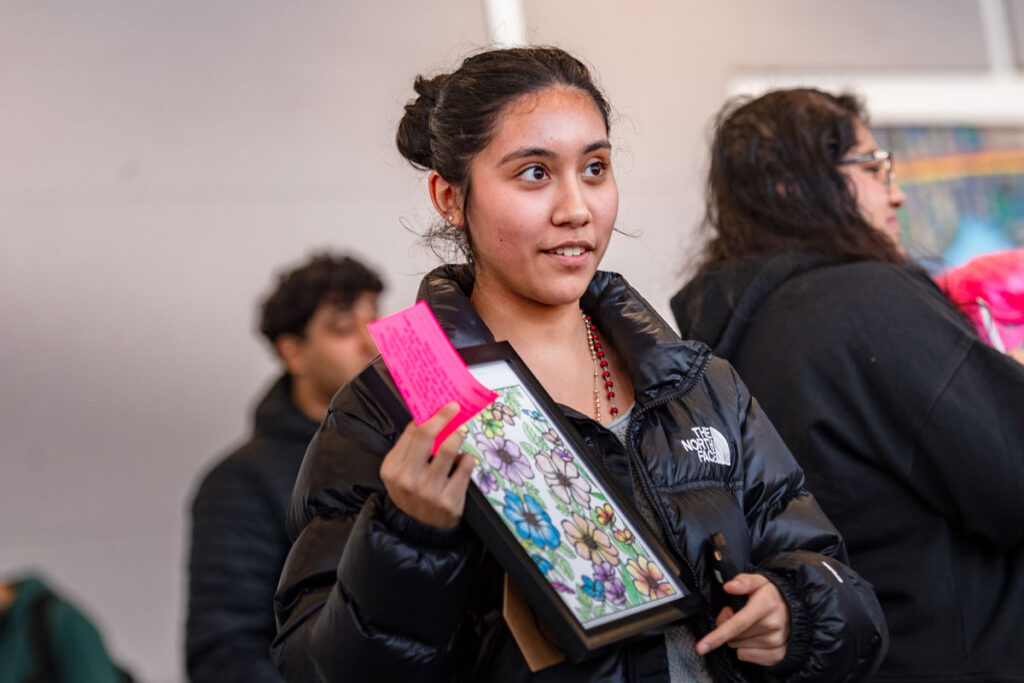 A person holding up a piece of artwork. 