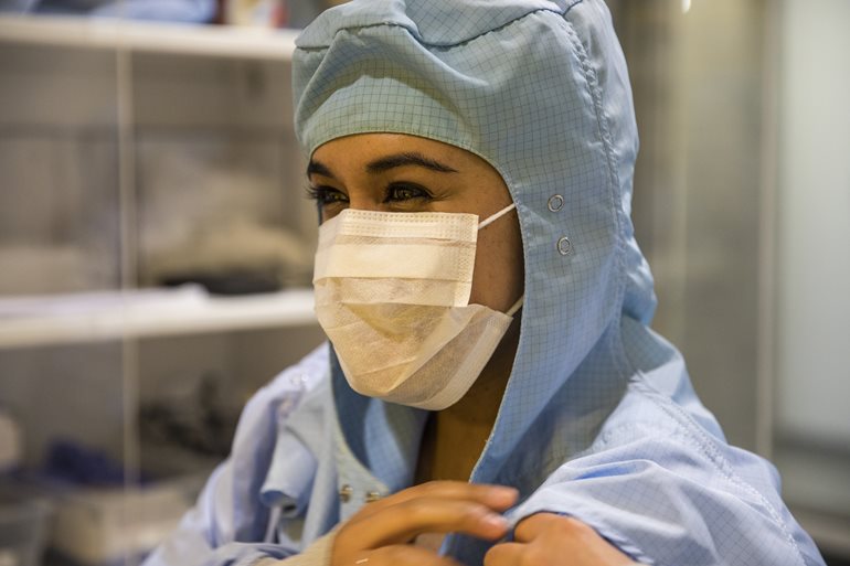 Malia Steward wearing a clean room mask and a blue clean suit.