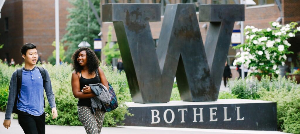 Two students walking past the "W" sculpture. 