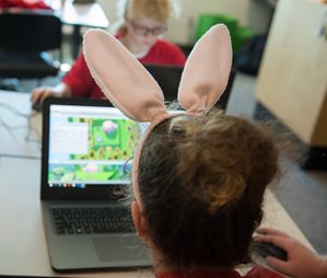 Child with bunny ears looking at computer