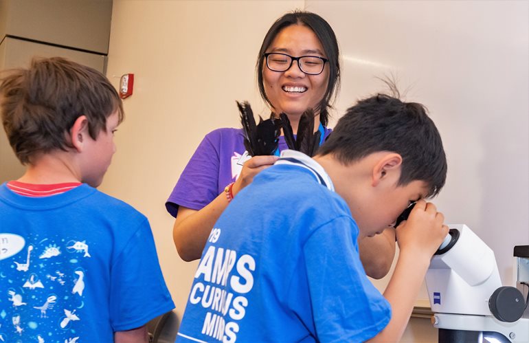 Instructor Nhu Ly and campers with microscope.