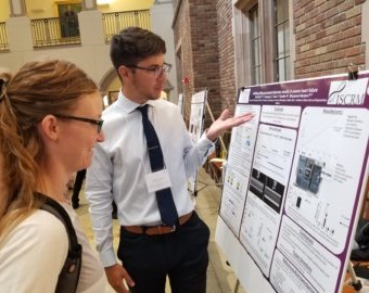 djelli berisha with another student looking at research poster