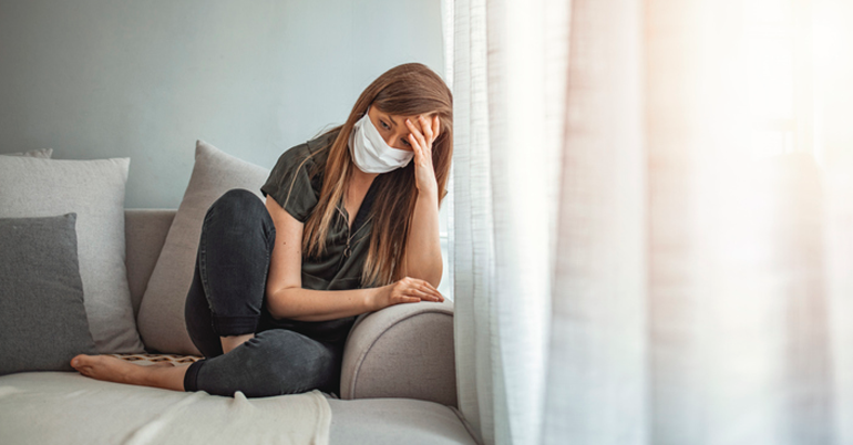 Lonely woman sitting on the couch with mask on
