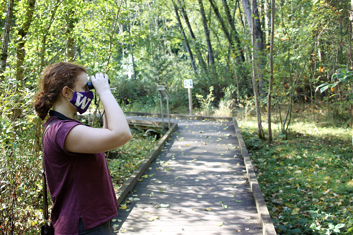 Kira looks through binoculars in the wetlands